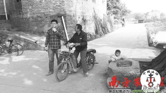 2月26日，侯锦强（左）在村中路上与村民聊村务。