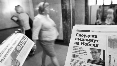 7月2日，在俄罗斯首都莫斯科的一个地下通道里，人们手持刊登关于斯诺登消息的报纸。俄罗斯总统新闻秘书佩斯科夫当天对媒体表示，原本有意留在俄罗斯的美国“棱镜”事件揭秘者斯诺登在得知俄总统普京提出的条件后已经放弃留俄打算。（新华社/路透）